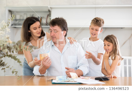 Happy father giving money to children in the kitchen Happy father giving money to children in the kitchen 136496523