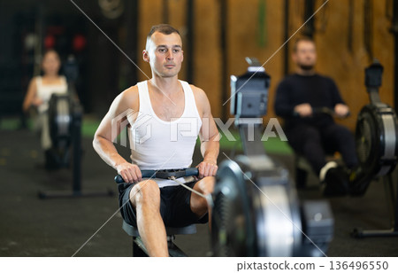 Man exercising on rowing machine during high intensity workout Man exercising on rowing machine during high intensity workout 136496550