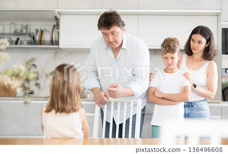 At home in kitchen, parents scold their daughter for careless act 136496608