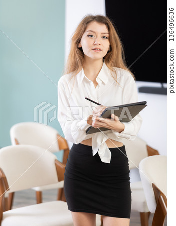Young female secretary with tablet invites in lecture hall 136496636