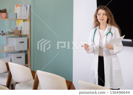 Girl doctor speaker with paper data report during lecture 136496644