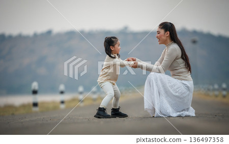 happy mother and child girl holding hands on road near the lake happy mother and child girl holding hands on road near the lake 136497358
