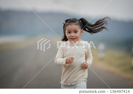 Energetic little child girl running happily on an open road by the water Energetic little child girl running happily on an open road by the water 136497414