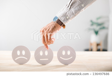 Customer satisfaction survey concept, hand selecting neutral face emoji for feedback, experience quality review illustrating choice among sad neutral happy ratings service evaluation table Customer satisfaction survey concept, hand selecting neutral face emoji for feedback, experience quality review illustrating choice among sad neutral happy ratings service evaluation table 136497686