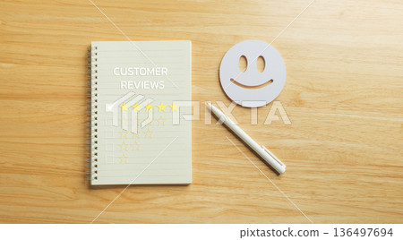 Feedback collection for customer satisfaction survey, showing five star review rating on notebook, happy face icon, pen on wood table, representing excellent service experience and quality assessment 136497694