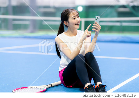 網球場上拿著智慧型手機的女子 136498139