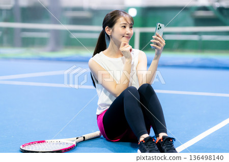 網球場上拿著智慧型手機的女子 136498140
