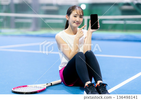 網球場上拿著智慧型手機的女子 136498141
