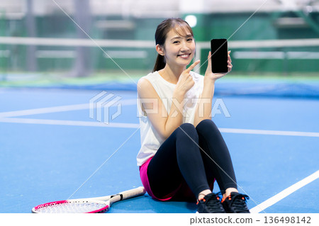 網球場上拿著智慧型手機的女子 136498142