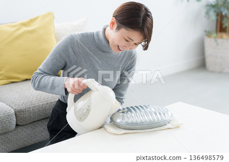 一位血液循環不良的女士正在熱水袋裡倒熱水 136498579