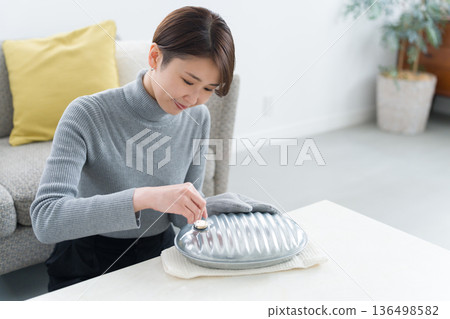 一位血液循環不良的女士正在熱水袋裡倒熱水 136498582