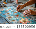 hands applying intricate paper cutouts in a decoupage art process 136500956