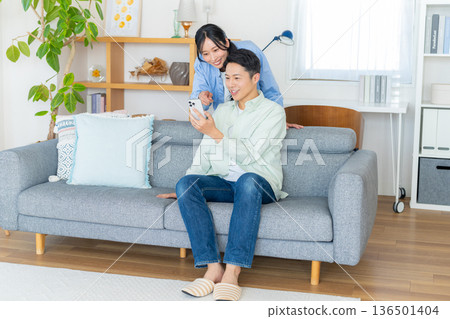 夫婦在客廳裡看智能手機 夫婦在客廳裡看智能手機 136501404