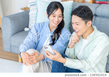 couple looking at smartphone in living room couple looking at smartphone in living room 136501414