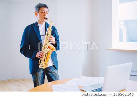 Senior man practicing the saxophone at home 136502146