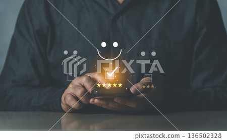 Close-up of a Person Interacting with Smartphone and Icons Representing Feedback and Customer Satisfaction in a Modern Conceptual Setting Close-up of a Person Interacting with Smartphone and Icons Representing Feedback and Customer Satisfaction in a Modern Conceptual Setting 136502328