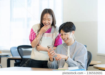 Students talking while looking at their smartphones Students talking while looking at their smartphones 136502691