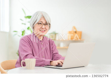 一位銀髮老婦人在客廳使用電腦。 一位銀髮老婦人在客廳使用電腦。 136502774