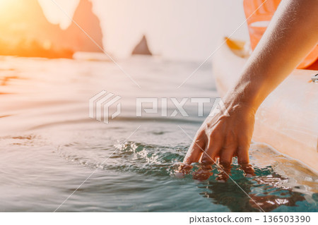 Kayaking Water Hand - A hand reaches into the water from a kayak, with rocky cliffs in the background. 136503390