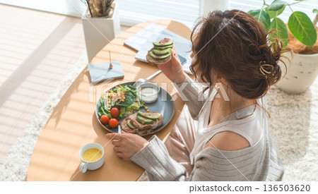 Stylish young Asian woman eating at the living room table Stylish young Asian woman eating at the living room table 136503620
