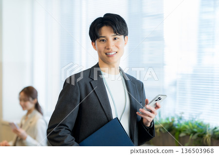 一個在辦公室使用智能手機的商人 一個在辦公室使用智能手機的商人 136503968