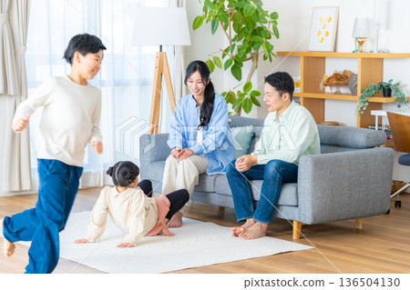 A family of four enjoying a relaxing time in the living room 136504130