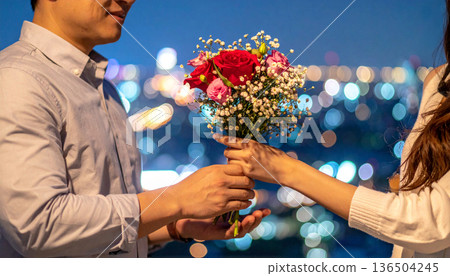 A man giving a bouquet and a woman receiving it 136504245