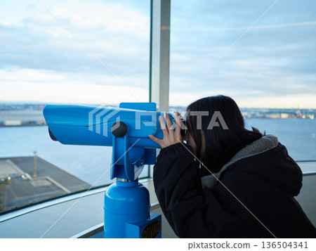 An elementary school girl looks at the scenery through binoculars at the observation deck of the Nagoya Port Building An elementary school girl looks at the scenery through binoculars at the observation deck of the Nagoya Port Building 136504341