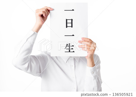 一個穿著白襯衫的人拿著一張紙，上面寫著「一日一命」。 136505921