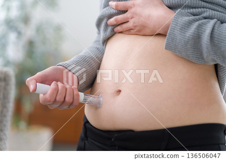 A woman injecting diet pills into her stomach (self-injection) A woman injecting diet pills into her stomach (self-injection) 136506047
