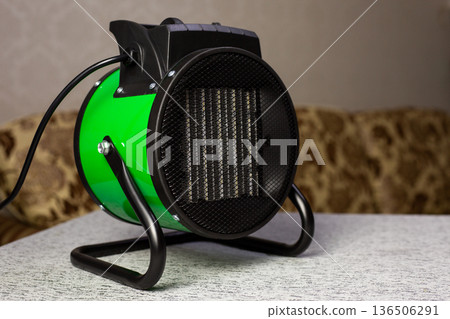 Industrial heat gun for heating large rooms, electric heater in living room. Electric heat gun warming the house indoors. Portable heater for rising temperature in cold room 136506291