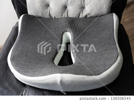 Orthopedic coccyx cushion for ergonomic seating comfort. Gray contoured memory foam pillow designed for office chair support, posture correction. Orthopedic coccyx cushion for ergonomic seating comfort. Gray contoured memory foam pillow designed for office chair support, posture correction. 136506545