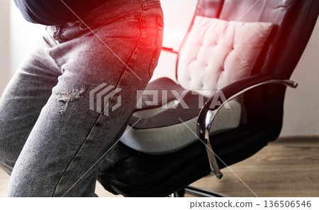 Person using orthopedic seat cushion for lower back pain, finding support for spinal discomfort. Ergonomic chair accessory aids posture and provides relief from disc issues. Medical aid for chronic 136506546