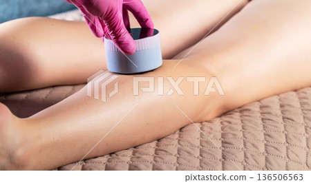 The hand of a cosmetologist makes an anti-cellulite massage with a portable vacuum massager, close-up, effective 136506563