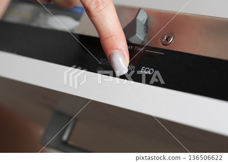 Close up view of woman finger pressing button on dishwasher control panel for starting washing program choosing eco mode. Power saving mode 136506622