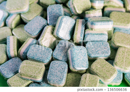 Pile of individually wrapped dual-color dishwasher tablets. Close-up view of cleaning products for dishwashing machine. Pile of individually wrapped dual-color dishwasher tablets. Close-up view of cleaning products for dishwashing machine. 136506636