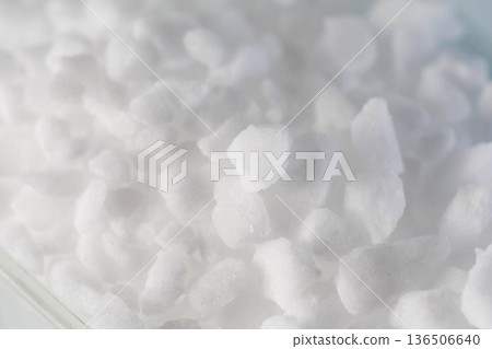 White crystalline substance close up showing irregular shapes and rough textures of granular material for water softening or industrial use. White crystalline substance close up showing irregular shapes and rough textures of granular material for water softening or industrial use. 136506640
