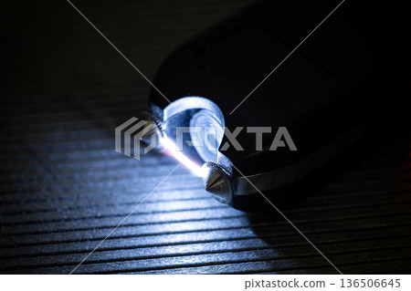 Close up view of electroshocker creating electric arc between metal prongs demonstrating danger and power of self defense device in dark environment. 136506645
