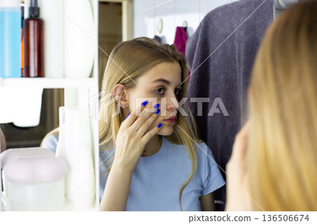 Real girl examines her skin in bathroom mirror. Importance of healthy skin for girl. Young girl touches her skin and examines imperfect areas. Worried about skin problems, girl takes care of herself Real girl examines her skin in bathroom mirror. Importance of healthy skin for girl. Young girl touches her skin and examines imperfect areas. Worried about skin problems, girl takes care of herself 136506674