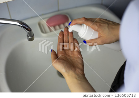 Woman hand squeeze facial cleanser onto her hand. Skin cleanser bottle with special dispenser for saving product. Concept for using skin cleanser foam with convenient packaging 136506718