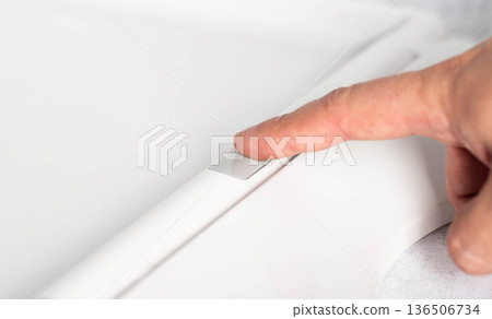 Close-up of finger pressing button on modern toilet seat cover to remove and disengage, close-up Close-up of finger pressing button on modern toilet seat cover to remove and disengage, close-up 136506734