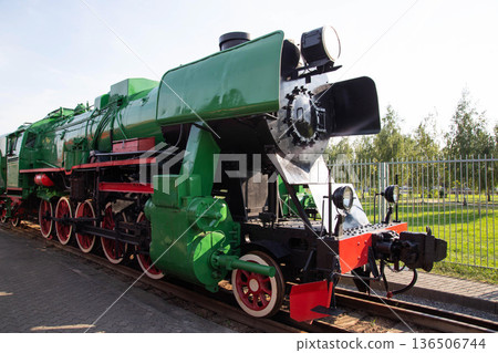 Vintage steam locomotive on display in a park during a sunny day with green trees in the background Vintage steam locomotive on display in a park during a sunny day with green trees in the background 136506744