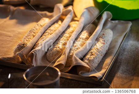Unbaked bread loaves proofing on baking sheet, ready for baking process, artisan bakery preparation, sourdough culture, rustic kitchen setting Unbaked bread loaves proofing on baking sheet, ready for baking process, artisan bakery preparation, sourdough culture, rustic kitchen setting 136506768