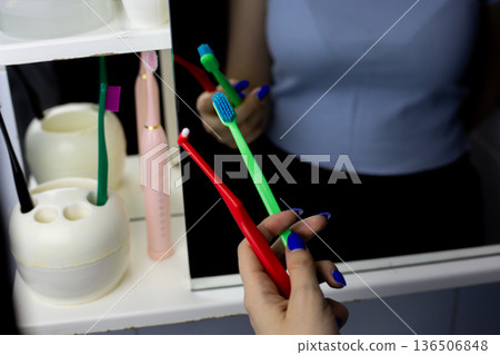 Girl holds two oral care brushes. Regular toothbrush and single tuft toothbrush. Set of tools for removing germs from gums and teeth. Brushes for removing dirt under braces 136506848