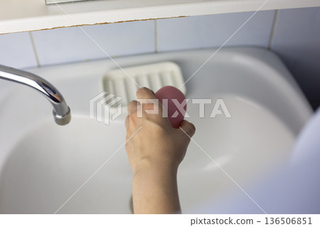 Woman holding soap against bathroom sink. Lived-in interior is in background. Process of handwashing in imperfect bathroom. Authentic photo of daily handwashing routine Woman holding soap against bathroom sink. Lived-in interior is in background. Process of handwashing in imperfect bathroom. Authentic photo of daily handwashing routine 136506851
