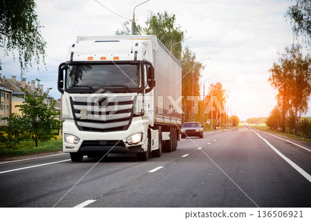 White semi truck with cargo trailer drives on rural highway road, transport of goods, logistic delivery, industry freight business, long haul trucking 136506921