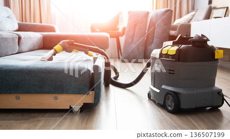 Professional sofa cleaning with powerful washing vacuum cleaner in living room interior, close up view of cleaning nozzle on fabric upholstery Professional sofa cleaning with powerful washing vacuum cleaner in living room interior, close up view of cleaning nozzle on fabric upholstery 136507199