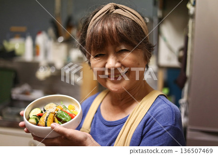 一個女人做油炸夏季蔬菜 136507469