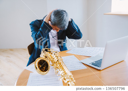 一位薩克斯風手抱著頭，憂心忡忡地看著樂譜。 136507796