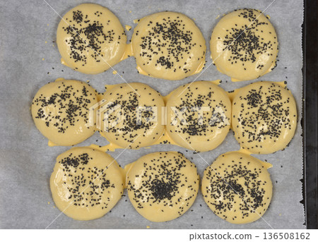 Raw burger buns with black sesame seeds on a baking sheet Raw burger buns with black sesame seeds on a baking sheet 136508162